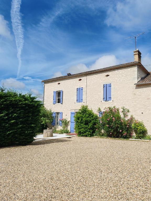 a white house with blue windows on a gravel driveway at Les Gîtes de Botte in Duras
