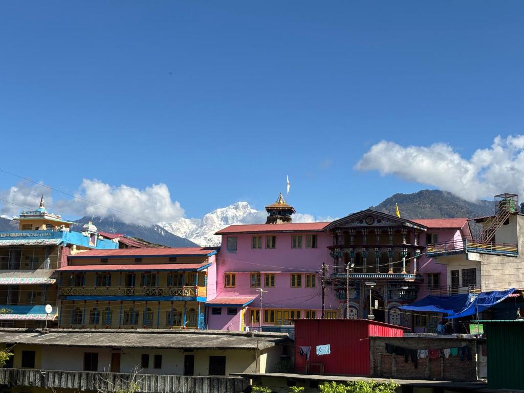 a group of buildings with mountains in the background at Hotel Om Palace in Ukhimath