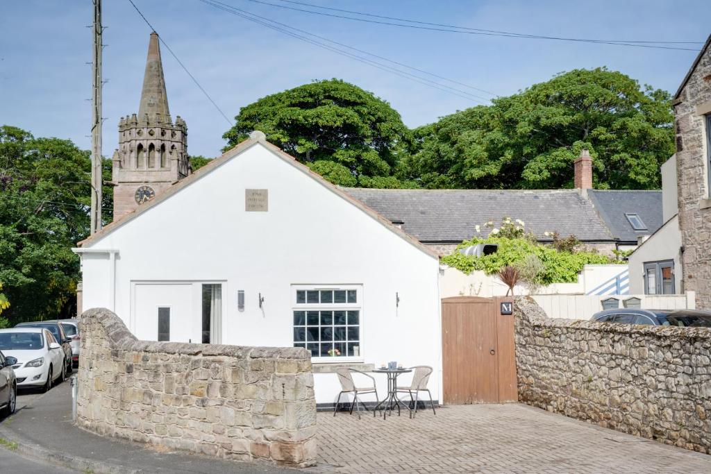 a white building with a fence and a church at Northern Hideaways, Iona Cottage in Newcastle upon Tyne