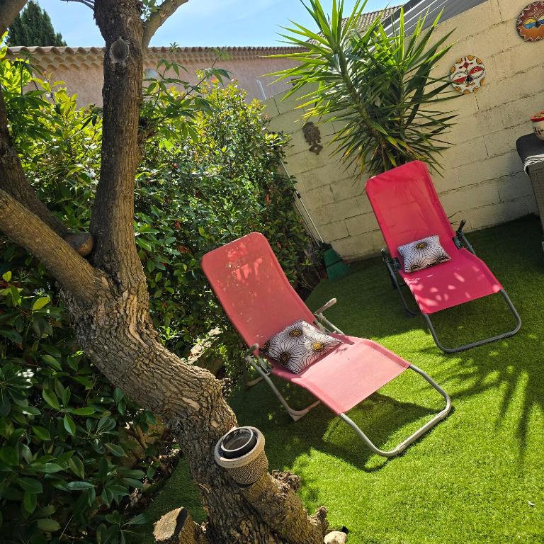 two lawn chairs sitting on the grass next to a tree at Maison Lauret in Agde