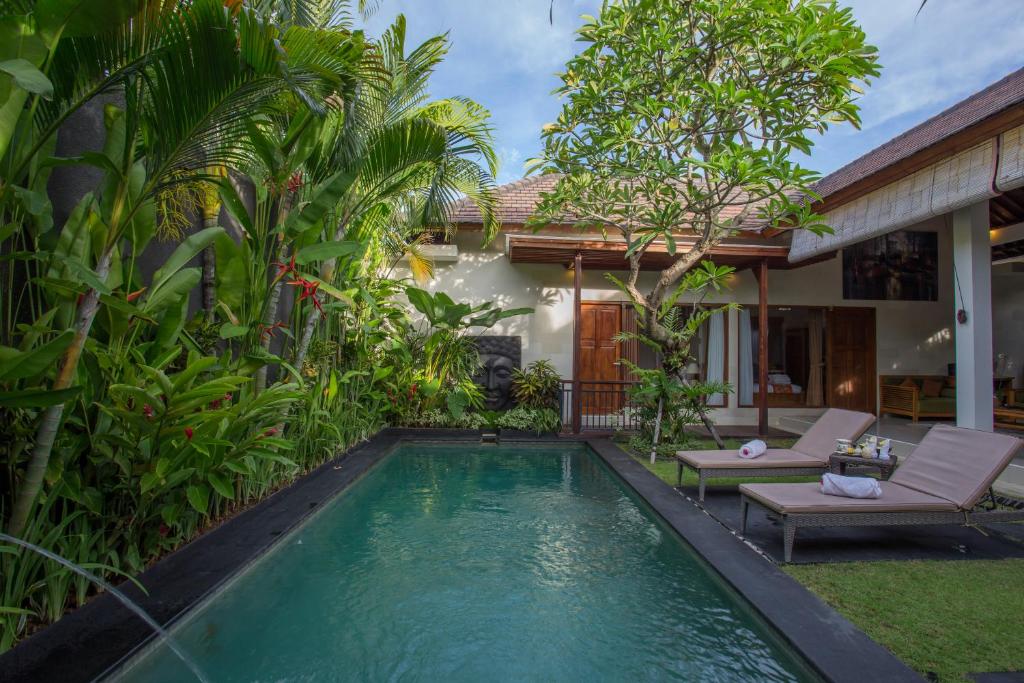 a swimming pool in front of a house with a villa at Sandi Agung Villa in Seminyak