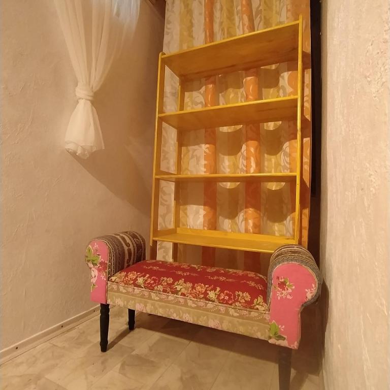 a chair in a corner with a shelf of cups at Ferienwohnung im Krokusweg in Langenneufnach
