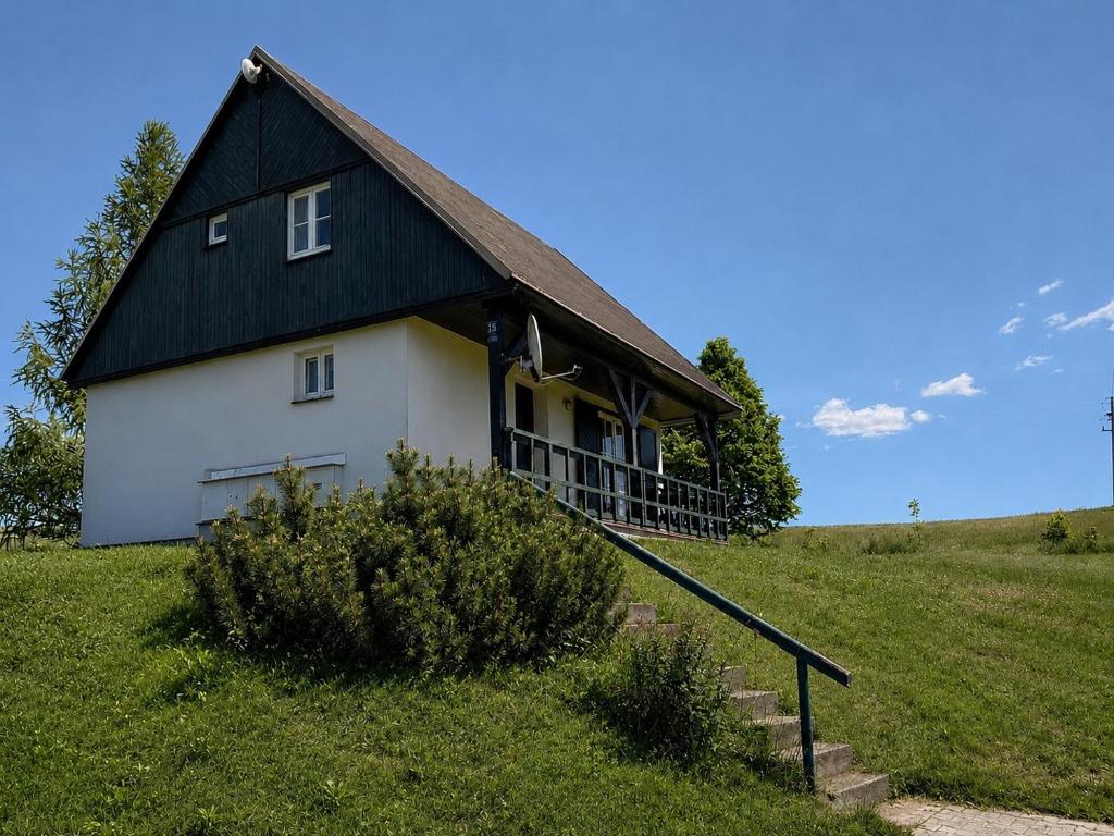 a white house with a black roof on a hill at Chata Křemenka in Lauterwasser