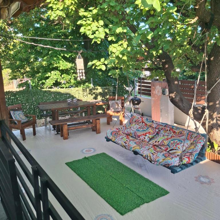 a porch with a hammock and a table and bench at Boho beach house in Nea Potidaea