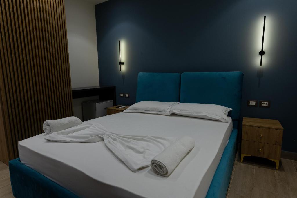 a blue bedroom with a bed with towels on it at Sea La Vie Hotel in Durrës