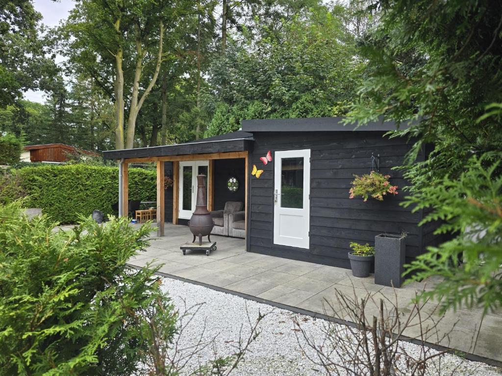a black tiny house in a garden with a patio at Chalet Del Sole in Voorthuizen