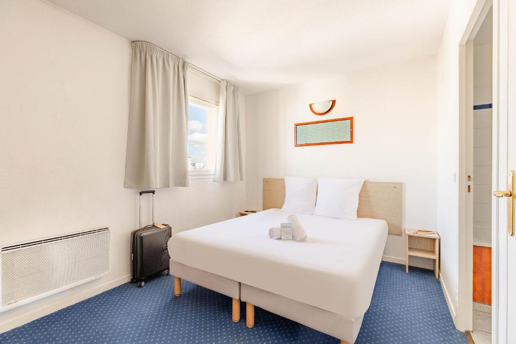 a hotel room with a white bed and a suitcase at Appart'City Classic Clermont Ferrand Centre in Clermont-Ferrand