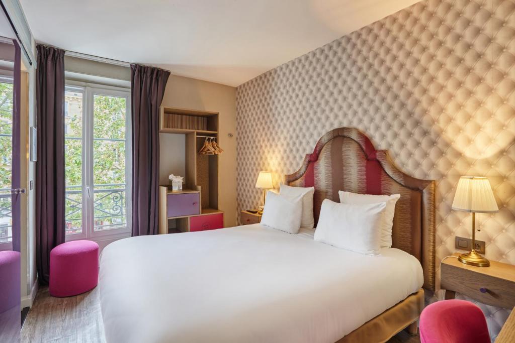 a bedroom with a white bed and a window at Hôtel La Parizienne - Proche Montparnasse in Paris