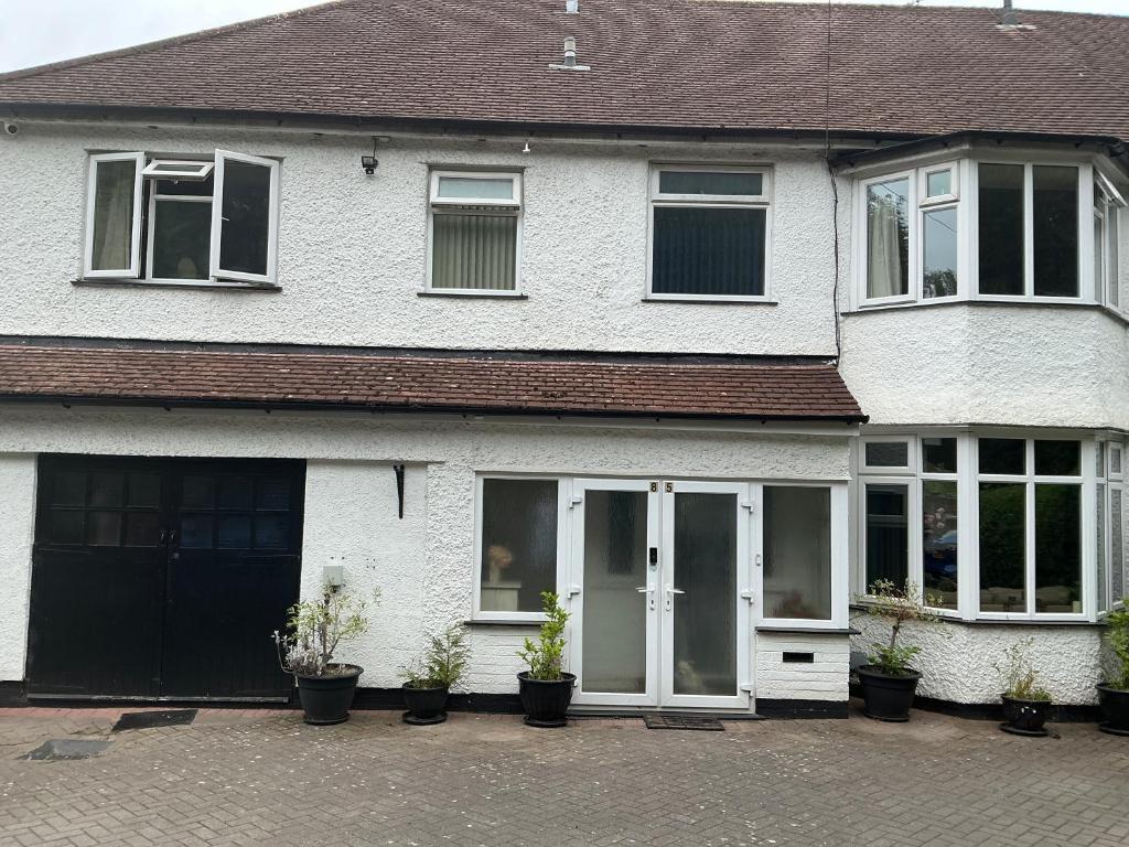 a white house with potted plants in front of it at Solihull Twin Room Wi-fi, TV in Solihull