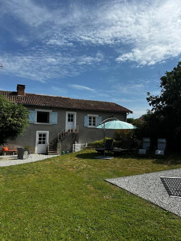 a white house with an umbrella in the yard at Le Nid Douillet in Chirac