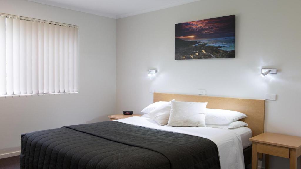 a bedroom with a bed and a picture on the wall at Boambee Bay Resort in Bonville
