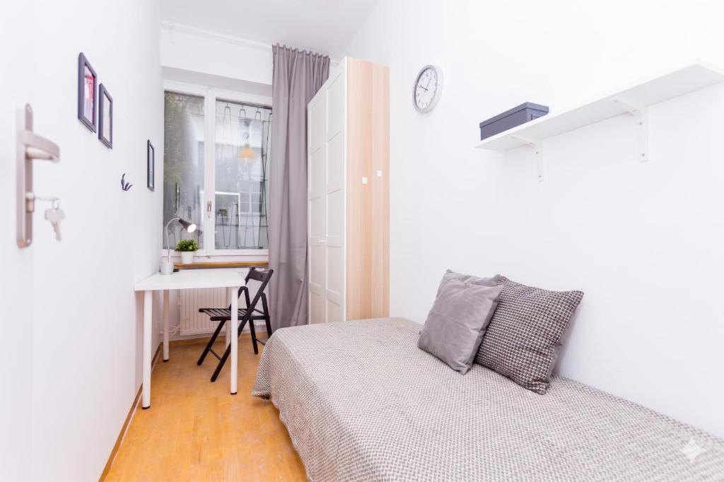 a small bedroom with a bed and a desk at Cozy Downtown Rooms in Warsaw