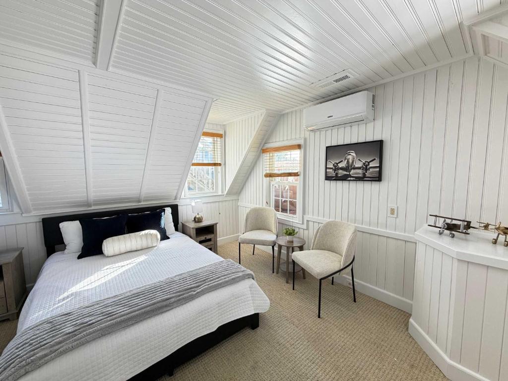 a bedroom with a bed and two chairs in it at 08-Flight Suite at The Castle Inn in Ocracoke