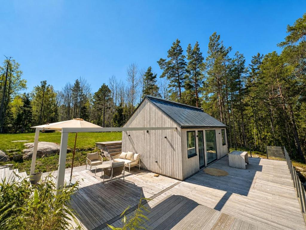 a wooden deck with a bench and an umbrella at Scandinavian Guesthouse, Archipelago Escape in Vaxholm