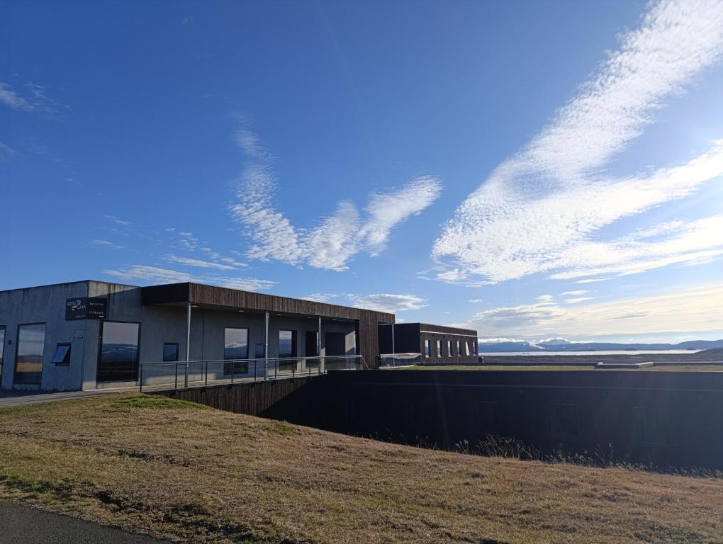 a building on the side of a field with a sky at Hótel Laxá in Myvatn