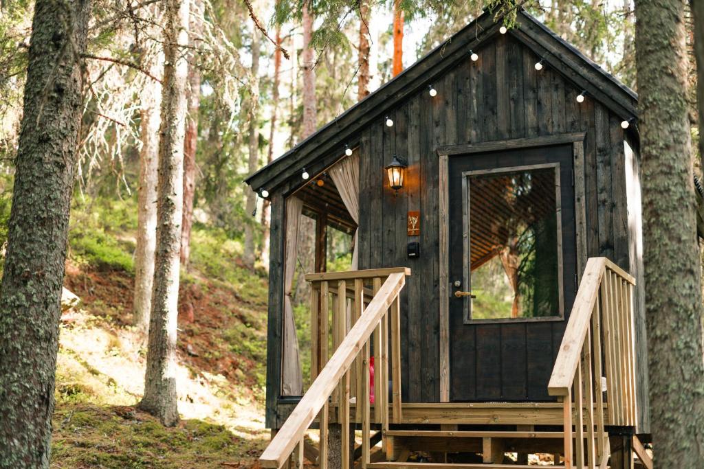 a black tiny house in the woods with a staircase at Minimökki Karjalohjalla in Lohja