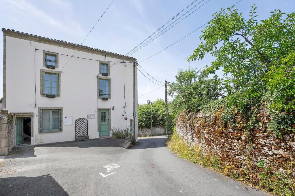 a white house with a green door on a street at Le Logis des Douves in Tiffauges