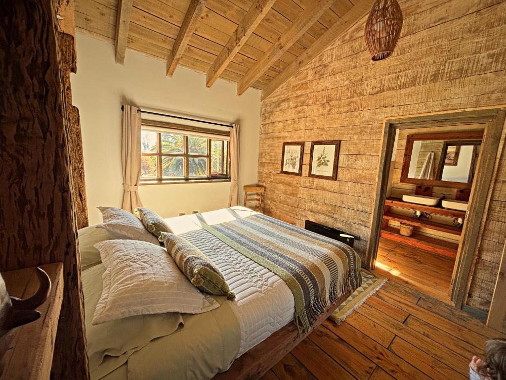 a bed in a room with a wooden wall at Casona el Refugio Casablanca in Casablanca