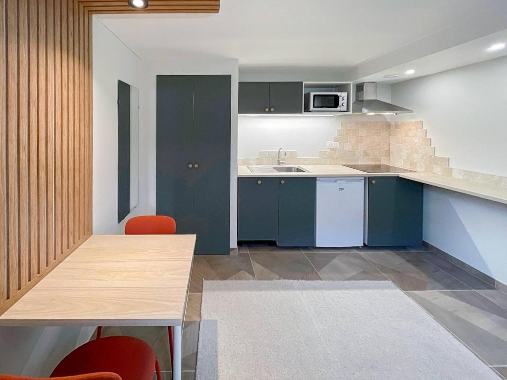 a kitchen with blue cabinets and a table with red chairs at Proche Luxembourg et centrale Cattenom in Hettange-Grande