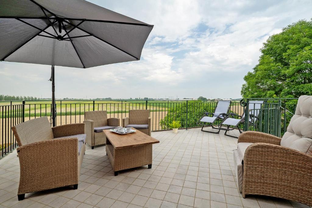 a patio with chairs and a table and an umbrella at Cozy Country Loft Oleandro in Chioggia