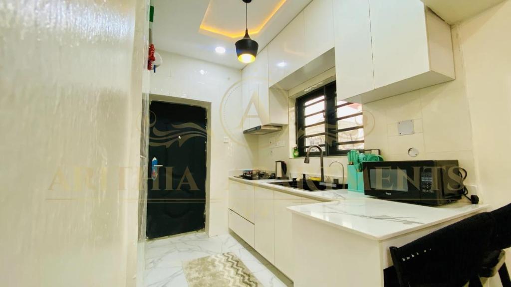 a white kitchen with a sink and a microwave at Arithia Apartments in Mama