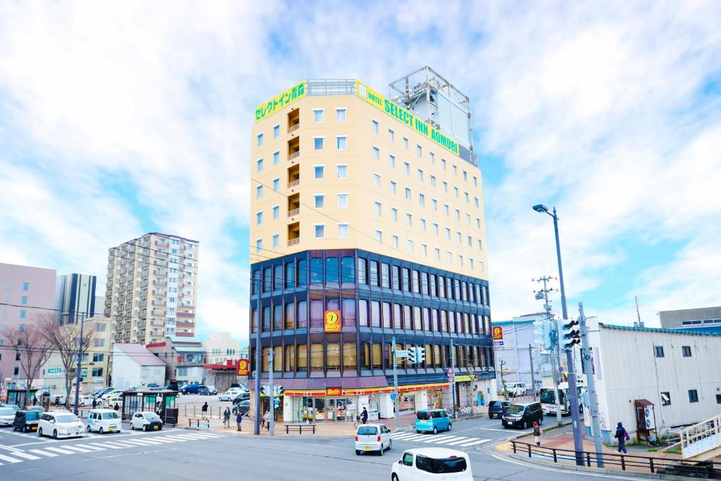 een hoog gebouw aan een drukke stadsstraat met auto's bij Hotel Select Inn Aomori in Aomori