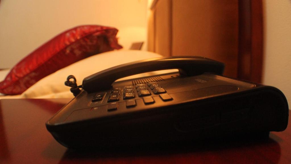 a black phone sitting on a table next to a bed at Hotel Residence Flamani in Lomé