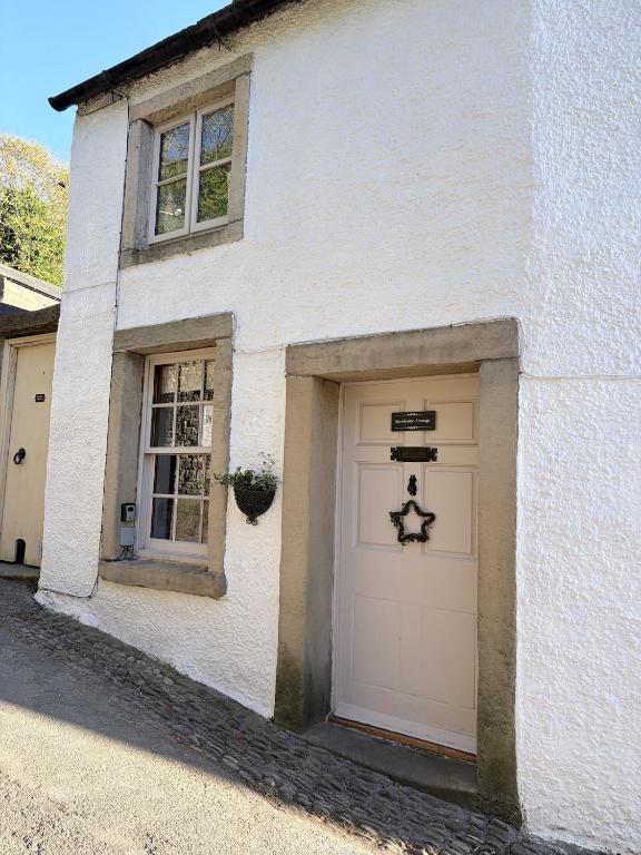 a white house with two garage doors and a window at Brewhouse Cottage 18th Century Cottage -Three Peaks Settle in Settle