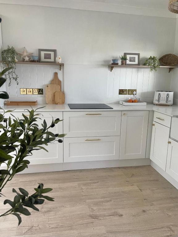 a kitchen with white cabinets and a counter top at Alder House Lytham in Lytham St Annes