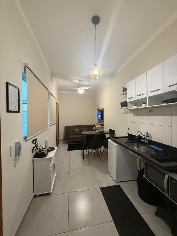 a kitchen with white cabinets and a table in it at Self check-in Garagem Ar 13 min ABQM in Araçatuba