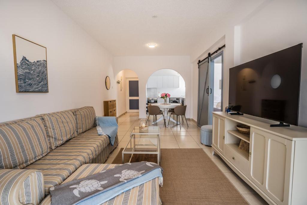 a living room with a couch and a flat screen tv at Aphrodite Breeze Paphos Gardens in Paphos