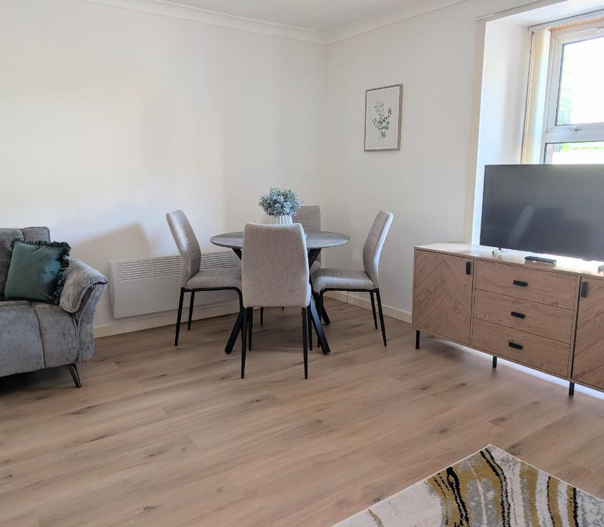a living room with a table and chairs and a tv at Glentorran in Campbeltown
