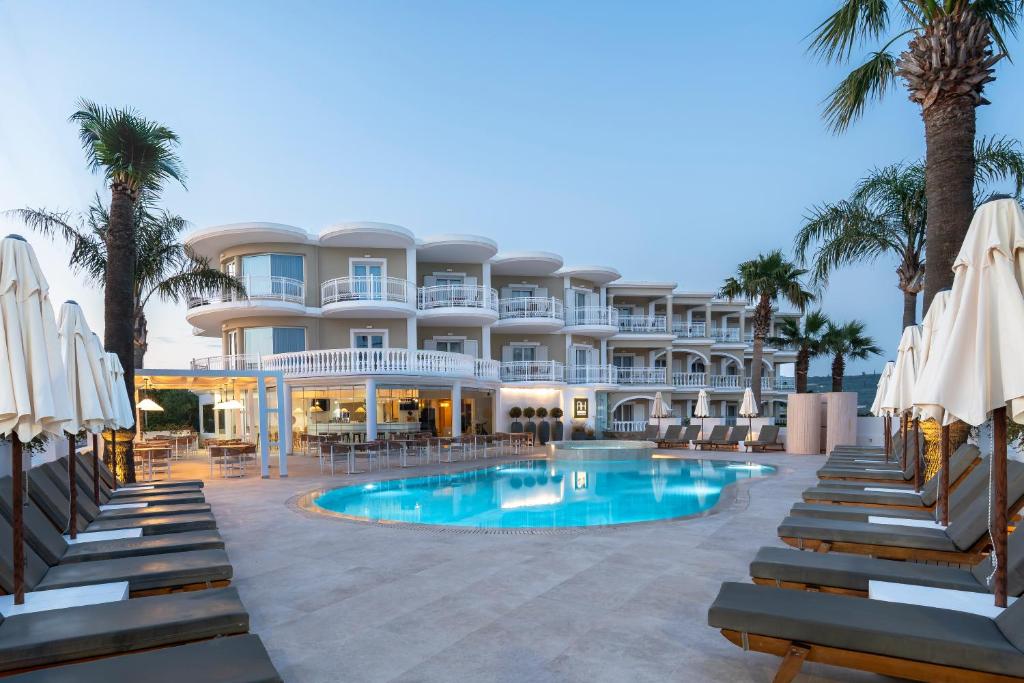 a resort with a swimming pool and palm trees and umbrellas at Arkadia Hotel in Kypseli