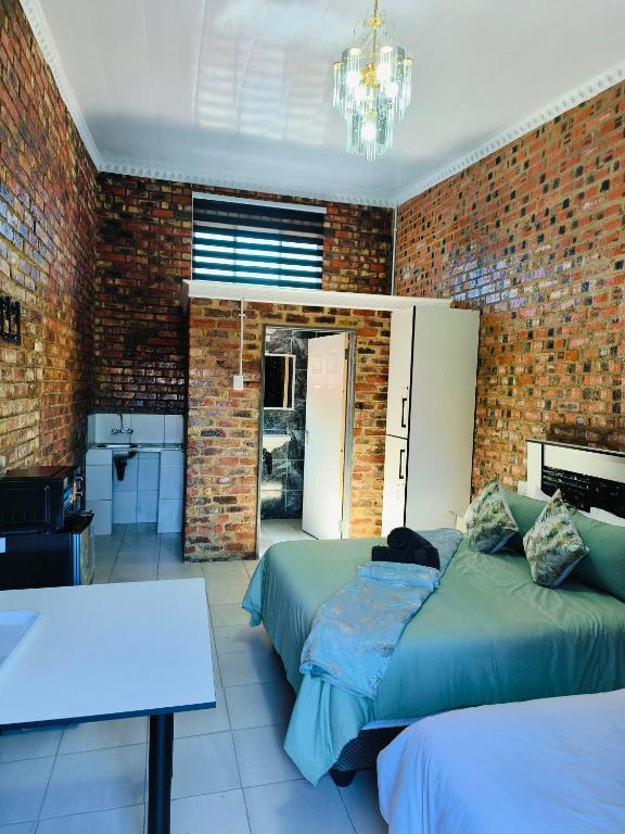 a bedroom with two beds and a brick wall at Acasa do Delco Accommodatiion in Welkom