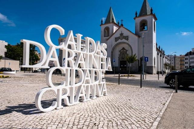 a large metal sign in front of a church at Apartamento Central Rainha in Caldas da Rainha