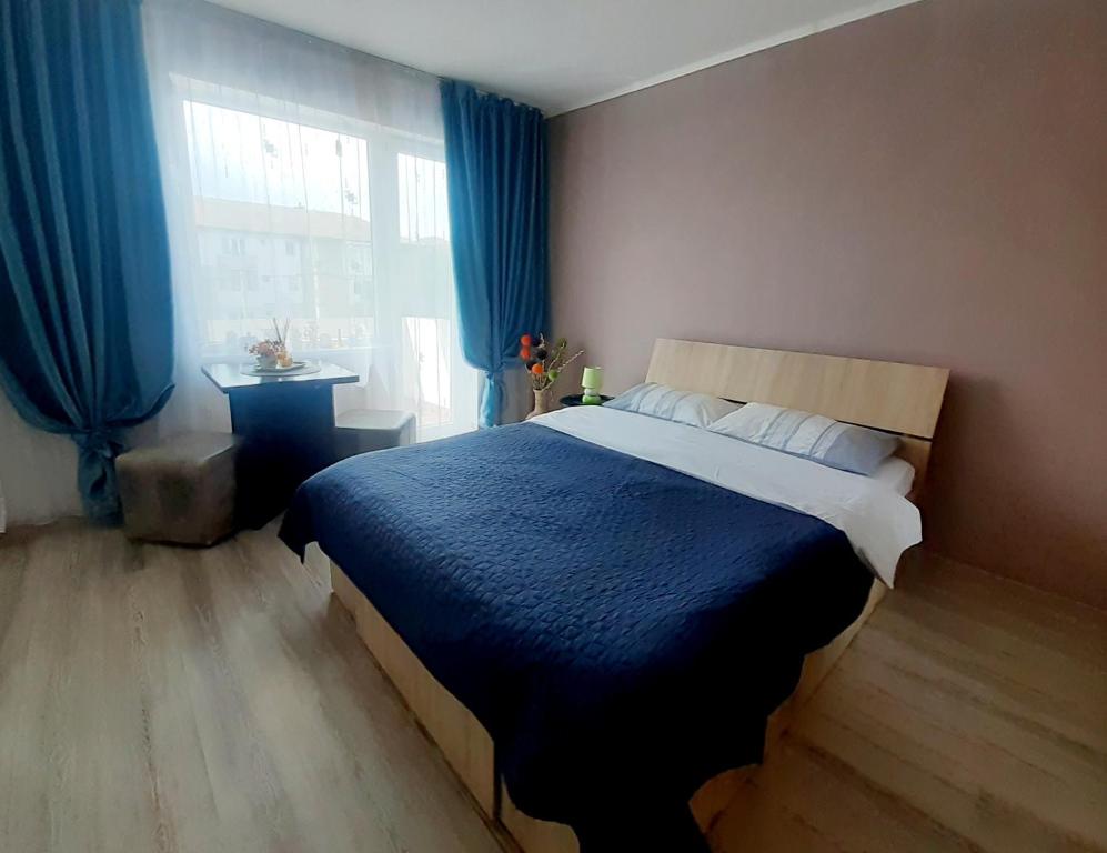 a bedroom with a bed with blue curtains and a window at Studio Ultracentral cu balcon in Onești