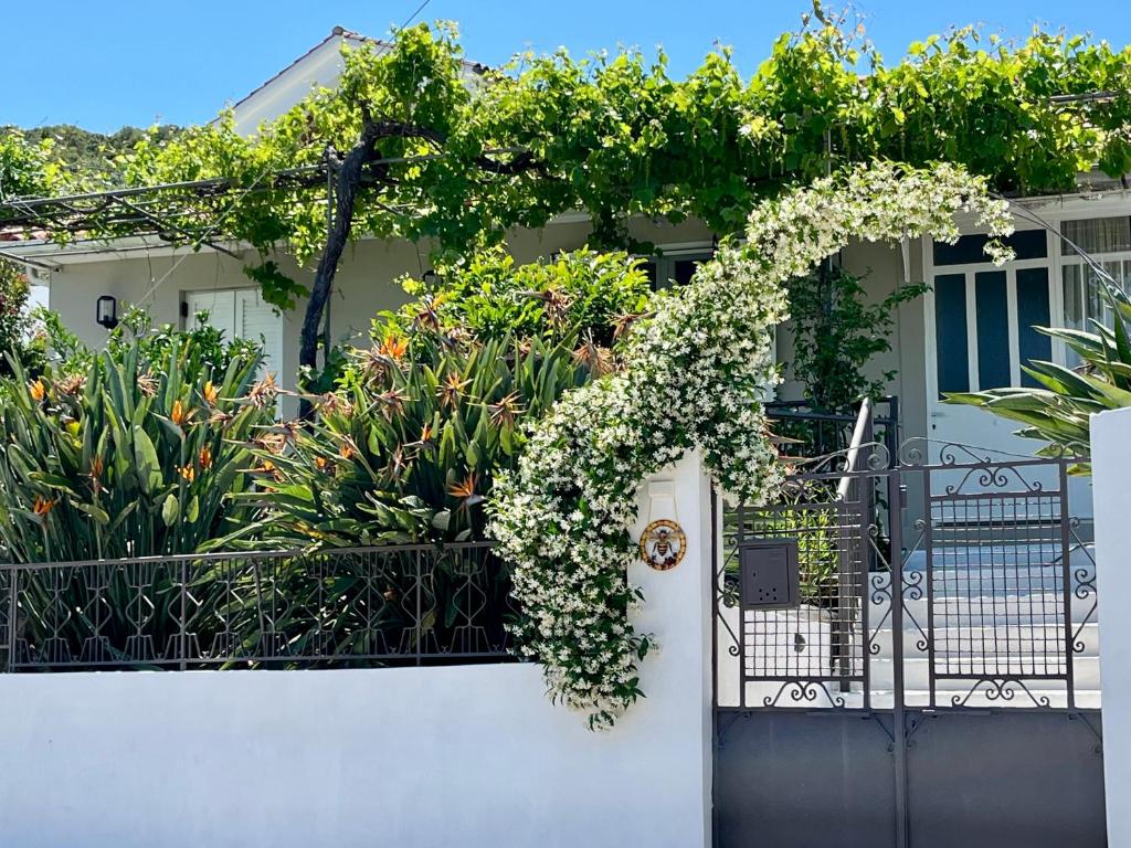 a white fence with a gate with flowers on it at Bee Home - Holiday Cottage in Agia Effimia