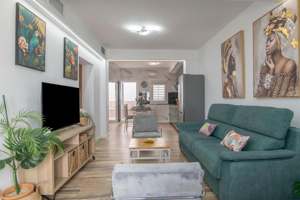 a living room with a blue couch and a tv at Casa Parque Benavente Conil in Conil de la Frontera
