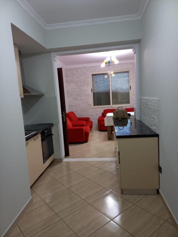 a kitchen and a living room with a red couch at Flodril Appartment in Durrës