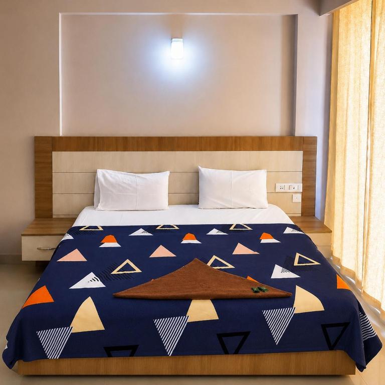 a bedroom with a bed with a blue comforter with triangles at Vrindavan Viharini Kunj in Chhatikara