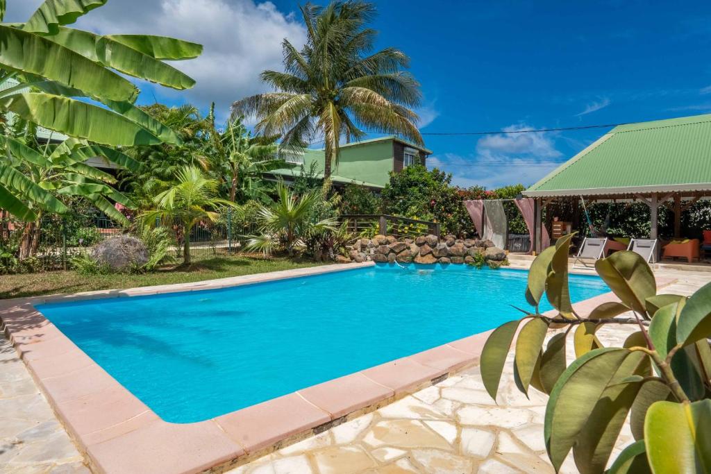 a swimming pool in front of a house with palm trees at Gites villa bagatelle piscine et Plage à 900m in Sainte-Rose
