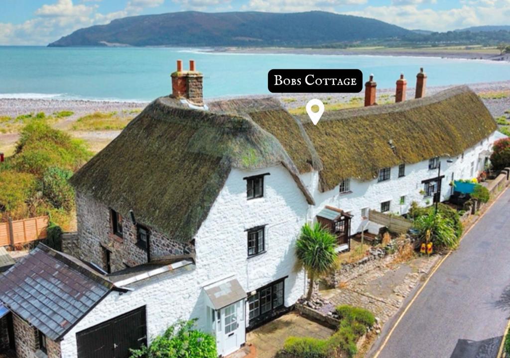 an old house with a thatched roof on the beach at Bobs Cottage Porlock Weir in Porlock