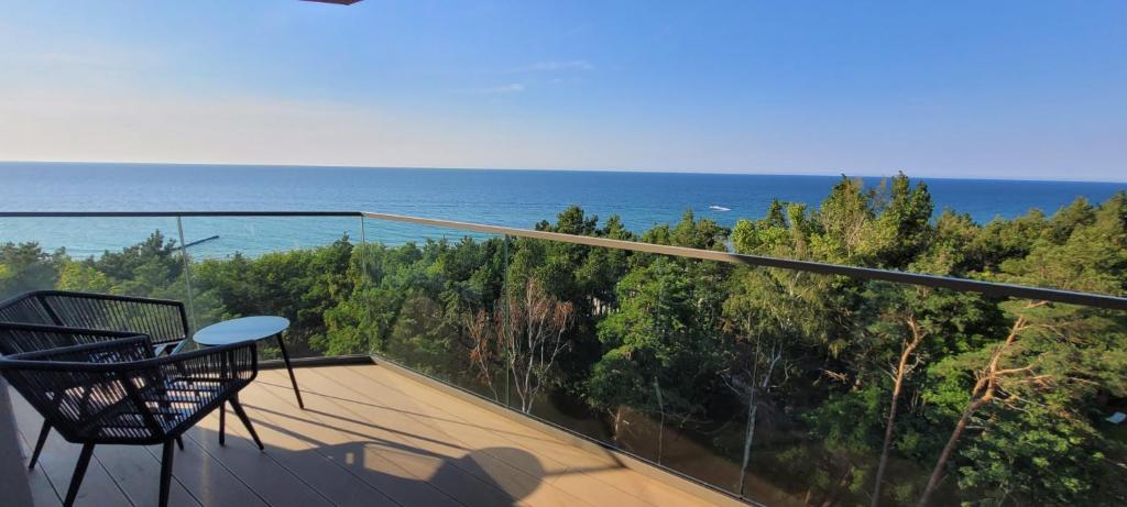 a balcony with a chair and a view of the ocean at PINEA Apartments tuż przy plaży - baseny, sauny, jacuzzi in Pobierowo