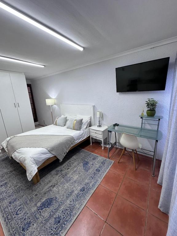 a bedroom with a bed and a table and a television at Protea Hoogte Flatlet in Brackenfell