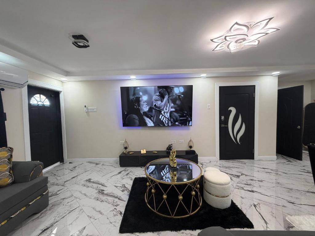 a living room with a couch and a tv on the wall at Elysium Noire in Spanish Town