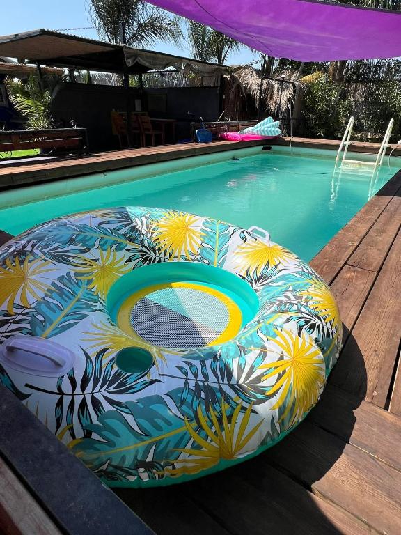 a swimming pool with a pool noodle sitting next to a swimming pool at פרא בקתות אירוח - מתחם נופש כפרי עם בריכה פרטית in Nir Yafe