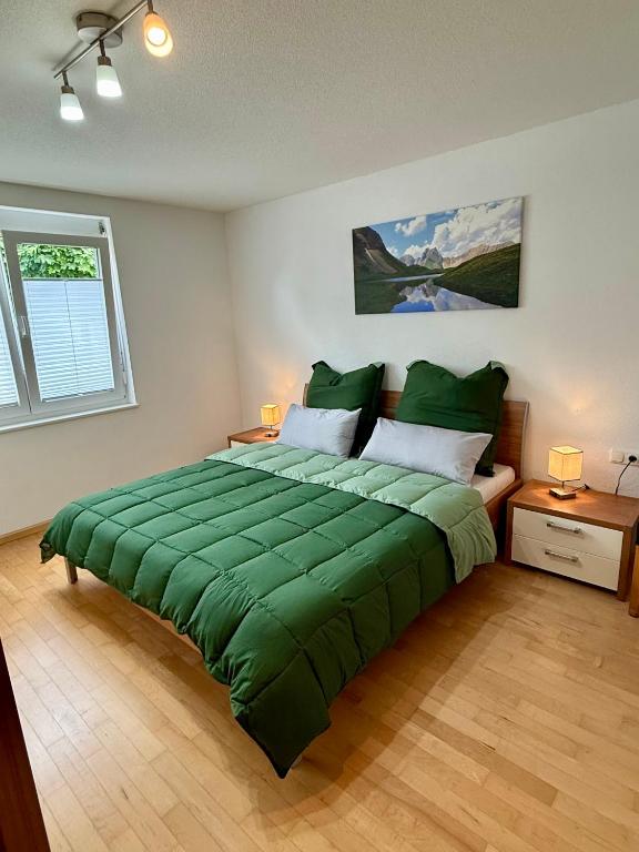 a bedroom with a large green bed with two lamps at Ferienwohnung Bodenseeblick in Hagnau