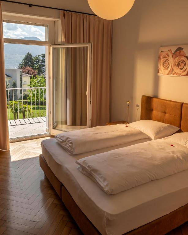 a bedroom with two beds and a large window at Das Filipinum in Merano
