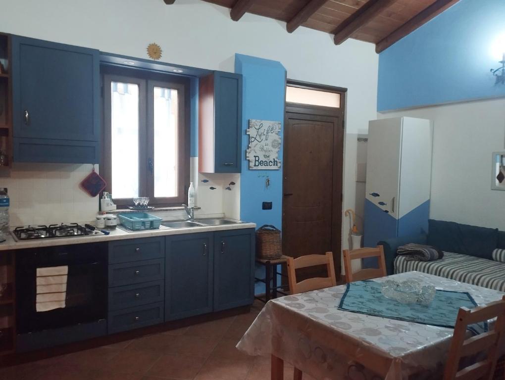 a kitchen with blue cabinets and a table with a table sidx sidx sidx at La casetta del pescatore - Le case di Bettina in Torrenova