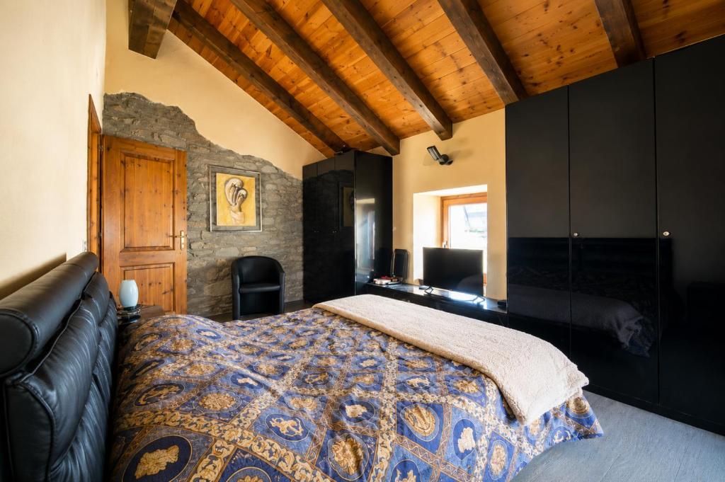a bedroom with a bed and a leather couch at The Old Barn by Roby in Saint Vincent